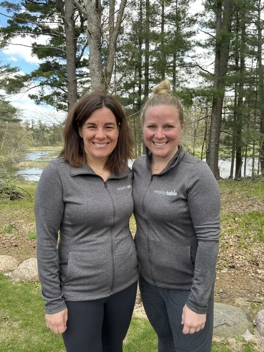 Co-Founders Betsy and Lora in front of a lake outside