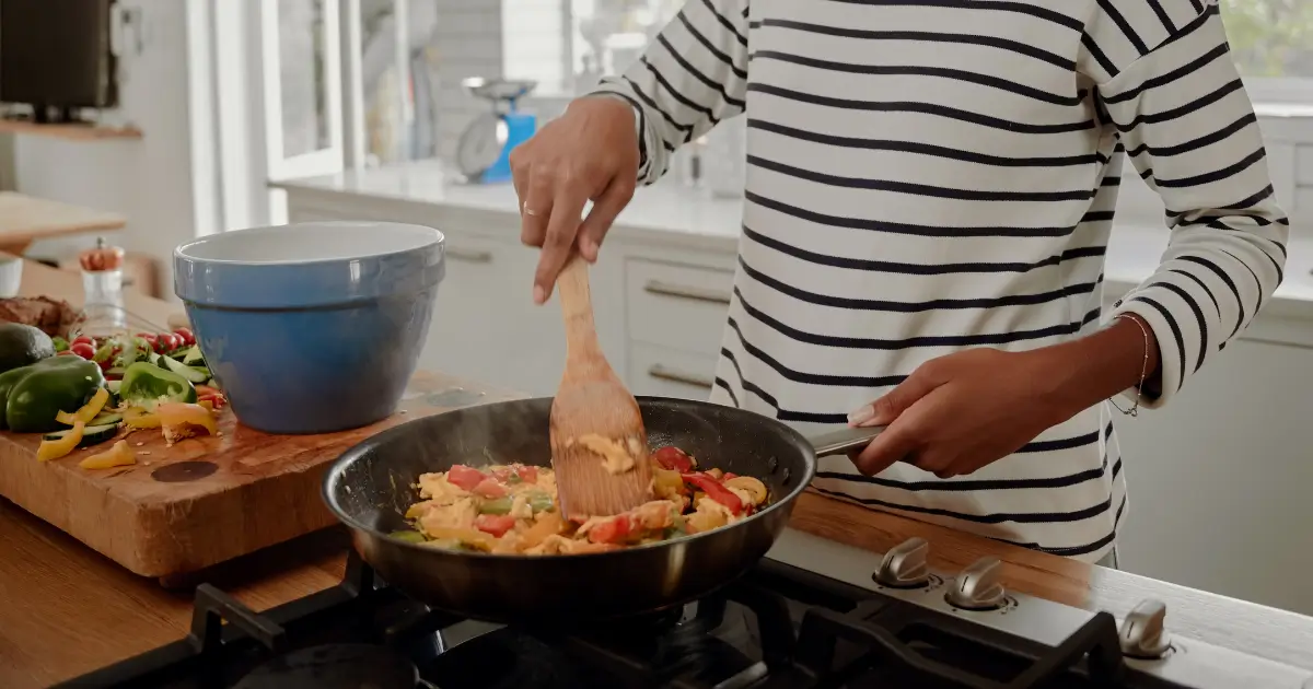 Woman stirring fajitas over the stove.